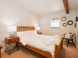 A bedroom with a wooden bed and bedside tables with lamps at Ysgubor Maen Y Bardd in Rowen near Conwy