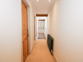 A hallway with wooden doors a black radiator a carpet runner and exposed wooden beams at Ysgubor Maen Y Bardd in Rowen near Conwy