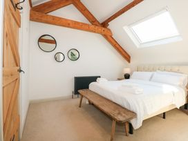 A bedroom with a bed white linens wooden bench mirrors on the wall and a skylight at Ysgubor Maen Y Bardd Rowen near Conwy