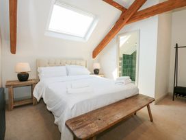 A bedroom with a bed with white linens two bedside tables with lamps wooden bench and skylight at Ysgubor Maen Y Bardd in Rowen near Conwy