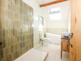 A bathroom with a tiled shower area a toilet a freestanding bathtub a sink on a wooden vanity and a skylight at Ysgubor Maen Y Bardd in Rowen near Conwy