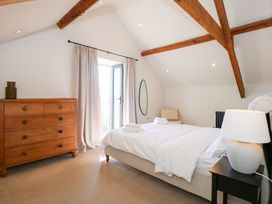 A bedroom with a double bed bedside table with a lamp wooden dresser chair and an oval mirror at Ysgubor Maen Y Bardd in Rowen near Conwy