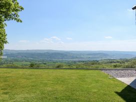 A grassy lawn with a glass fence overlooking hills and valleys at Ysgubor Maen Y Bardd in Rowen near Conwy