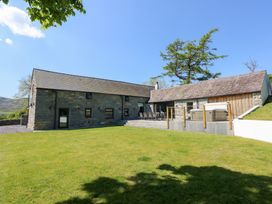 Exterior view of a stone house with a patio and outdoor dining set on a grassy lawn at Ysgubor Maen Y Bardd Rowen near Conwy