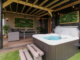 An outdoor lounge area with a hot tub and seating at Hazel in Oakthorpe near Donisthorpe