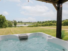 A hot tub with a view of a lake and grassy area at Hazel Oakthorpe near Donisthorpe