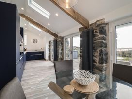 A kitchen and dining area with blue cabinets wooden beams and glass doors opening to a patio at Gaerau Bach in Llanaber
