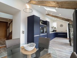 A kitchen with blue cabinets a glass dining table with a white bowl and wooden placemats at Gaerau Bach in Llanaber