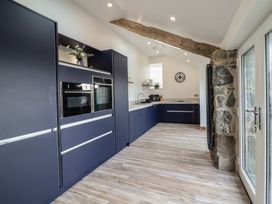 A kitchen with blue cabinets wooden beam and stone wall at Gaerau Bach in Llanaber