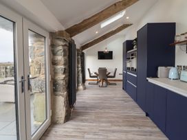 A kitchen and dining area with blue cabinets wooden beams and glass doors at Gaerau Bach in Llanaber