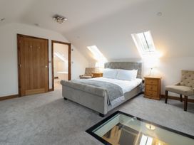 A bedroom with a bed two chairs two wooden nightstands and skylight windows at Gaerau Bach in Llanaber