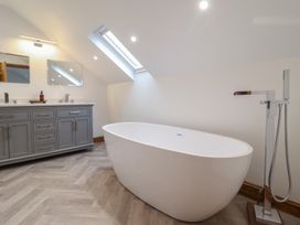A bathroom with a freestanding bathtub a gray vanity with two mirrors and a skylight window at Gaerau Bach in Llanaber