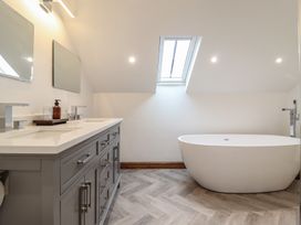 A bathroom with a freestanding bathtub a gray vanity with two sinks two mirrors and a skylight at Gaerau Bach in Llanaber