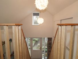 A stairway with wooden railings leading down to a door with glass panels and a pathway outside at The Studio at Dan y Garn in Newport Pembrokeshire