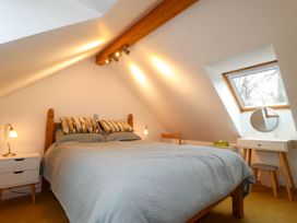 A bedroom with a wooden bed two bedside tables lamps a dressing table and a window at The Studio at Dan y Garn in Newport Pembrokeshire