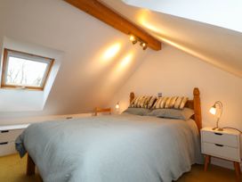A bedroom with a double bed bedside table and a window at The Studio at Dan y Garn in Newport Pembrokeshire