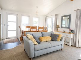 A living room with a grey sofa and wooden dining table at 32 Sanctuary Lodge in Y Ffor