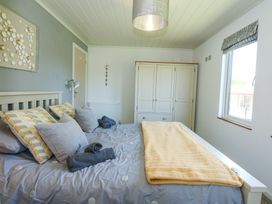 A bedroom with a bed with pillows and folded towels next to a window at 32 Sanctuary Lodge in Y Ffor