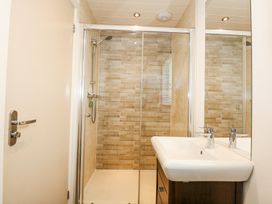 A bathroom with a glass shower enclosure and a sink with a mirror at 32 Sanctuary Lodge in Y Ffor