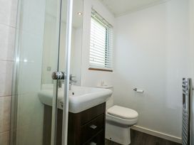 A bathroom with a sink cabinet toilet window with blinds and a shower cubicle at 32 Sanctuary Lodge in Y Ffor