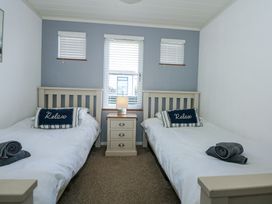 A bedroom with two single beds separated by a nightstand with a lamp at 32 Sanctuary Lodge in Y Ffor