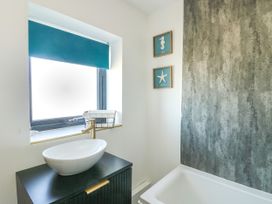 A bathroom with a sink and wall art at Iscoed in Rhosneigr