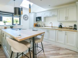 A kitchen with an island and stools at Iscoed in Rhosneigr