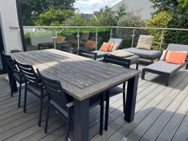 An outdoor patio with a dining table and loungers at Yonder Lea Bowness-On-Windermere