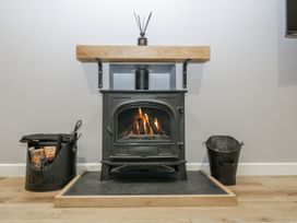 A wood stove with a shelf and log basket in Ranbir House Longhope