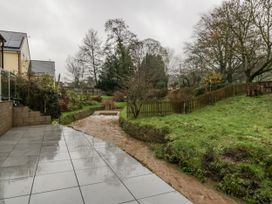 An outdoor patio area with a stream and trees at Ranbir House in Longhope