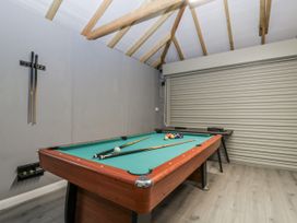 A pool table with cue sticks and a wall rack in a recreation room at Ranbir House Longhope