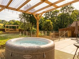 A hot tub on a patio with a pergola and garden area at Ranbir House in Longhope