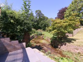 A garden with a stream and trees at Ranbir House in Longhope