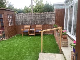 A garden with chairs and a wooden shed at Sandy Haven in Swanage