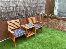 A garden with wooden chairs and a table at Sandy Haven in Swanage