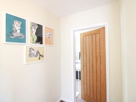 A hallway with framed artwork on the wall and a wooden door at Tansea in Hope Cove