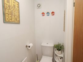 A bathroom with a toilet and wall art at Brucap Cottage in Beadnell