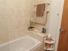 A bathroom with a bathtub, towels, and toiletries at Brucap Cottage in Beadnell