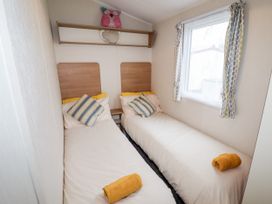 A small bedroom with two single beds pillows and towels by the window at B15 Ty Gwyn in Towyn