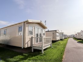 A row of beige and white caravans along a paved road on grass at B15 Ty Gwyn in Towyn