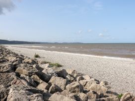 A rocky shoreline with a pebble beach and sea under a blue sky at B15 Ty Gwyn in Towyn