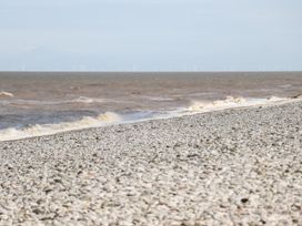 A pebble beach with waves and wind turbines in the sea at B15 Ty Gwyn in Towyn