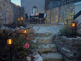 A garden with a table, chairs, and lanterns at Winkle Cottage in Weymouth