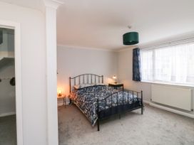 A bedroom with a black metal bed frame with floral bedding two side tables with lamps a window with blue curtains and a radiator at 1 Ilsham Cottages Torquay
