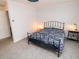 A bedroom with a bed with floral bedding and two bedside tables with lamps at 1 Ilsham Cottages in Torquay