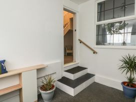 A small entryway with steps leading to a doorway and two potted plants near a window at 1 Ilsham Cottages in Torquay