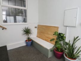 A corner with a wooden bench and three potted plants near a window and an electrical panel at 1 Ilsham Cottages Torquay