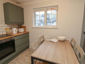 A kitchen with green cabinets a wooden dining table with chairs and a window at 1 Ilsham Cottages Torquay