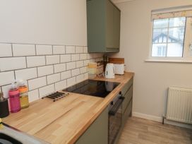 A kitchen with wooden countertops a black electric stove white kettle and toaster green cabinets and a window at 1 Ilsham Cottages in Torquay
