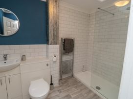 A bathroom with a toilet sink towel rack and a walk in shower at 1 Ilsham Cottages in Torquay